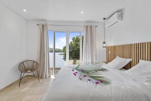 a bedroom with a large white bed with a window at Villa La Sucrerie in Les Anses-dʼArlets +26 photos