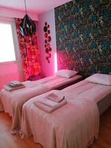 two beds in a room with pink walls at Asunto Kitee in Kitee