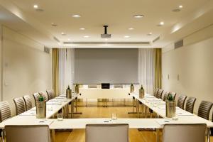 sala konferencyjna ze stołami i krzesłami oraz ekranem projekcyjnym w obiekcie UNA HOTELS Century Milano w Mediolanie