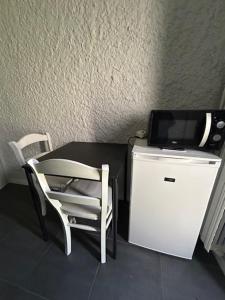 a room with a table and a tv and a chair at Chambre Au Trèfle Dort in Châtel-Guyon
