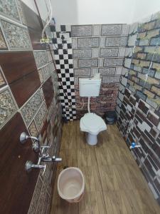 Un baño con inodoro y pared de azulejos. en Hotel Chacha's garden with restaurant pushkar, en Pushkar