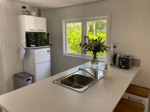 a kitchen counter with a sink and a refrigerator at Manuka Cottage Oneroa in Waiheke Island