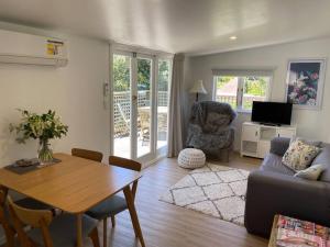 a living room with a table and a couch at Manuka Cottage Oneroa in Waiheke Island
