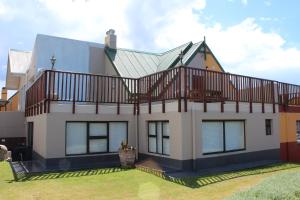 a house with a balcony on top of it at Holiday Villa Diaz Beach Mossel Bay in Mossel Bay