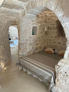 a room with a bed in a stone wall at Trullo KAVA - Ceglie Messapica in Ceglie Messapica