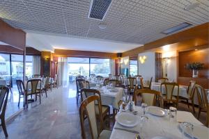 ein Restaurant mit weißen Tischen und Stühlen und Fenstern in der Unterkunft Esperia Hotel in Kavala
