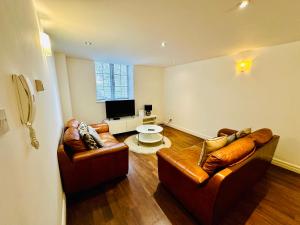 a living room with two leather couches and a television at West Street Mews - Serviced Accommodation in Exeter