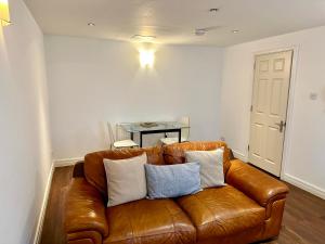 a brown leather couch in a living room with a table at West Street Mews - Serviced Accommodation in Exeter