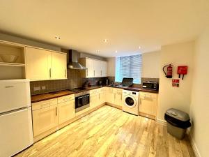 a kitchen with white cabinets and a washer and dryer at West Street Mews - Serviced Accommodation in Exeter
