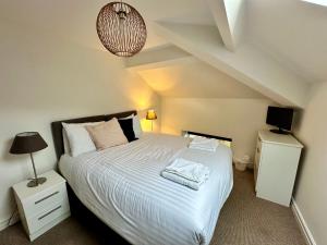 a bedroom with a large bed with white sheets and a lamp at West Street Mews - Serviced Accommodation in Exeter