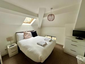 a bedroom with a white bed and a television at West Street Mews - Serviced Accommodation in Exeter