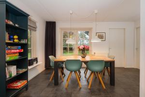 a dining room with a wooden table and green chairs at Buitengoed het Lageveld 62 in Hoge-Hexel