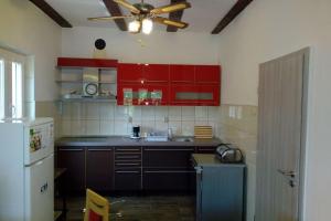 Una cocina con gabinetes rojos y un ventilador de techo. en Holiday House Soline, en Veli Rat
