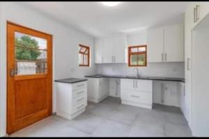 a kitchen with white cabinets and a wooden door at De Rust Karoo Cottages in De Rust +18 photos