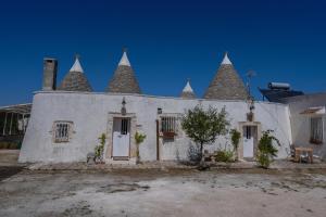 Un edificio blanco con torres puntiagudas en la parte superior. en I trulli di Mani', en Masseria Orimini