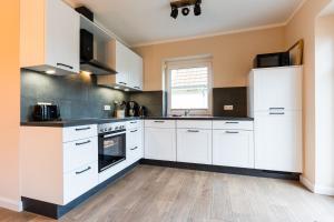 eine Küche mit weißen Schränken und einem Holzboden in der Unterkunft Schusterkate - [#96108] in Staberdorf