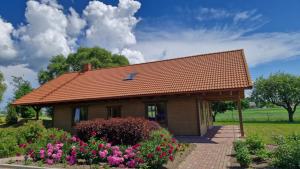 PenkuleOzoliņi的一座带红色屋顶和一些鲜花的小房子