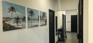 a hallway with four paintings of the beach at Villa Elenita - Pura Vida in Parrita