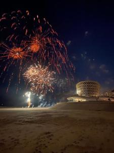 un espectáculo de fuegos artificiales en la playa con un edificio en el fondo en SeaSide Rendez-vous - Appartement 3 chambres Vue mer, piscine, sauna & parking à Middelkerke, en Middelkerke