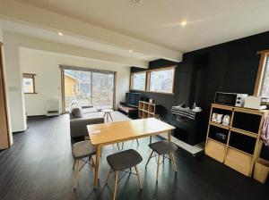 a living room with a wooden table and chairs at Hakuba Cottage ICHIZAEMON in Hakuba