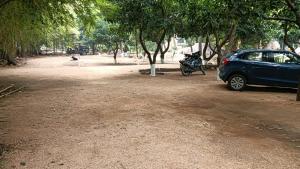 a blue car and a motorcycle parked next to trees at Saanvi Farmhouse in Hampi