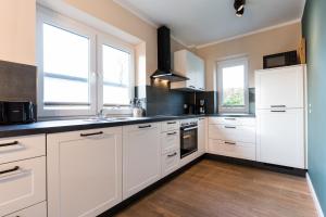 eine weiße Küche mit weißen Schränken und Fenstern in der Unterkunft Backhaus 4 in Staberdorf