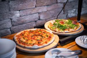 two pizzas sitting on top of a wooden table at Amenity Hotel & Resort Lipno in Lipno nad Vltavou