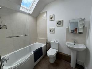 a bathroom with a white tub and a toilet and a sink at Y Mor Cosy Apartment in Tywyn