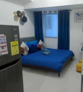 a bedroom with a bed with blue sheets and a window at Cozy Condo near US EmbassyErmita Manila/ Roxas blvd/ Dolomite beach in Manila