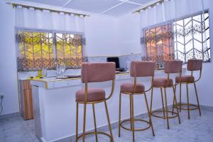 a kitchen with four bar stools at a counter at Private Villa & Tropical Garden Cottages near Bofa Beach - by Mango Tree Cottages Kilifi in Kilifi