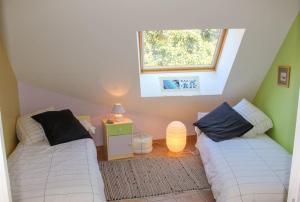 a attic room with two beds and a window at Gîte La Sittelle in Bellaffaire