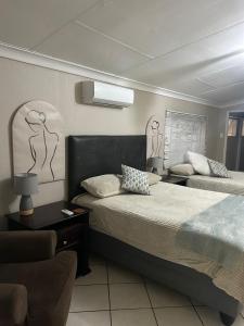 a hotel room with two beds and a chair at 9 wena Ave Guesthouse in Klerksdorp