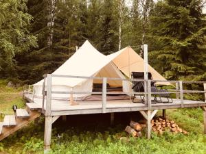 a large white tent on a wooden deck at Glamping tent in a forest, lake view in Bjuråker