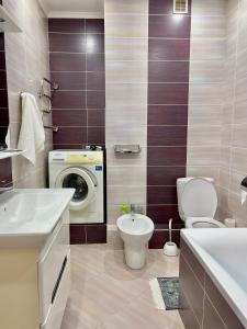 ein Badezimmer mit Waschmaschine und Toilette in der Unterkunft 205 Очень теплая 3 комн квартира у Байтерека с 3 большими кроватями и раскладным диваном для 1-8 человек in Astana + 11 Fotos