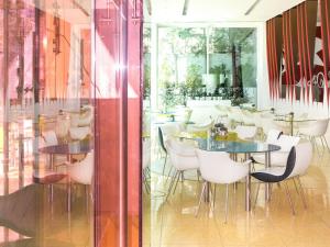 ein Restaurant mit weißen Stühlen, Tischen und Fenstern in der Unterkunft Semiramis, a Member of Design Hotels in Athen