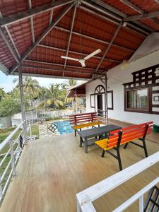 a patio with benches and a table and a pool at Villa Wistaria- Luxury 7BHK Villa With Private Pool in Alibaug