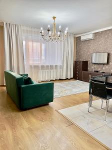 ein Wohnzimmer mit einer grünen Couch und einem Tisch in der Unterkunft 205 Очень теплая 3 комн квартира у Байтерека с 3 большими кроватями и раскладным диваном для 1-8 человек in Astana