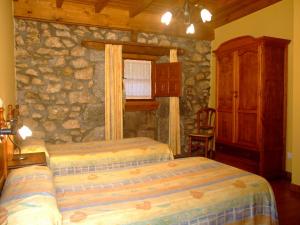 una camera da letto con due letti e un muro di pietra di Las Casucas de Ason ad Arredondo
