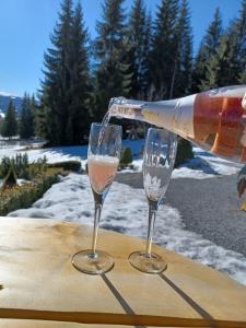 a bottle of wine being poured into two glasses at Pensiunea L`Amoro in Neagra Şarului