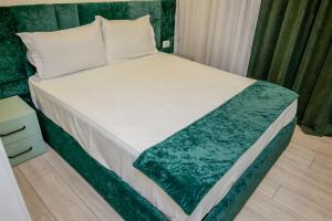 a bedroom with a bed with a green and white comforter at Vollgaapartment2 in Durrës