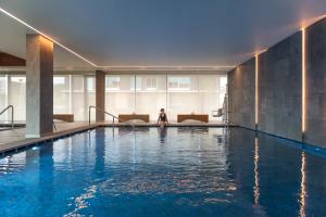 a woman is sitting in a swimming pool at Doubletree By Hilton Lagoa Azores in Lagoa