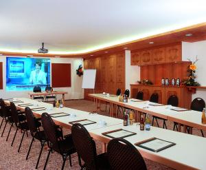 a conference room with tables and chairs and a screen at Waldhotel Geländer in Schernfeld