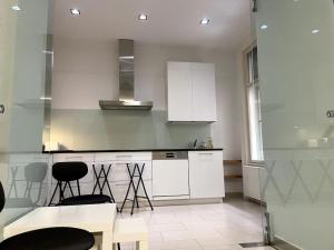 a kitchen with white cabinets and bar stools at Luxury Serviced 3-Bedroom Flat in Vienna's 1st District in Vienna +21 photos