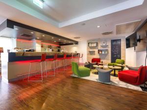 a restaurant with a bar with red and green chairs at ibis Stuttgart Airport Messe in Leinfelden-Echterdingen