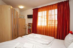 Schlafzimmer mit einem Bett und einem Fenster mit roten Vorhängen in der Unterkunft Strandvilla Böck FeWo 10 strandnah, Balkon, Meerblick in Glowe