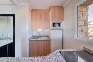 een kleine keuken met een spoelbak en een magnetron bij Playa Bajondillo Terrace - Free Parking in Torremolinos