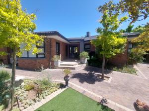 a brick house with a yard with grass and trees at 7Pillars Shiraz in Durbanville