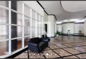 a living room with a black leather chair in a room with large windows at Apart511 in Santos