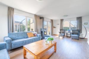 a living room with a blue couch and a table at Villapark Kamperfoelie 75 in De Koog