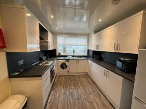 a kitchen with white cabinets and a washer and dryer at Myreslaw Green Apartment, Hawick Scottish Borders in Hawick